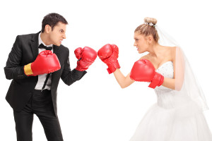 Young groom and a bride fighting each other with boxing gloves i