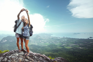 Happy couple with backpacks making a snapshot of themselves on t